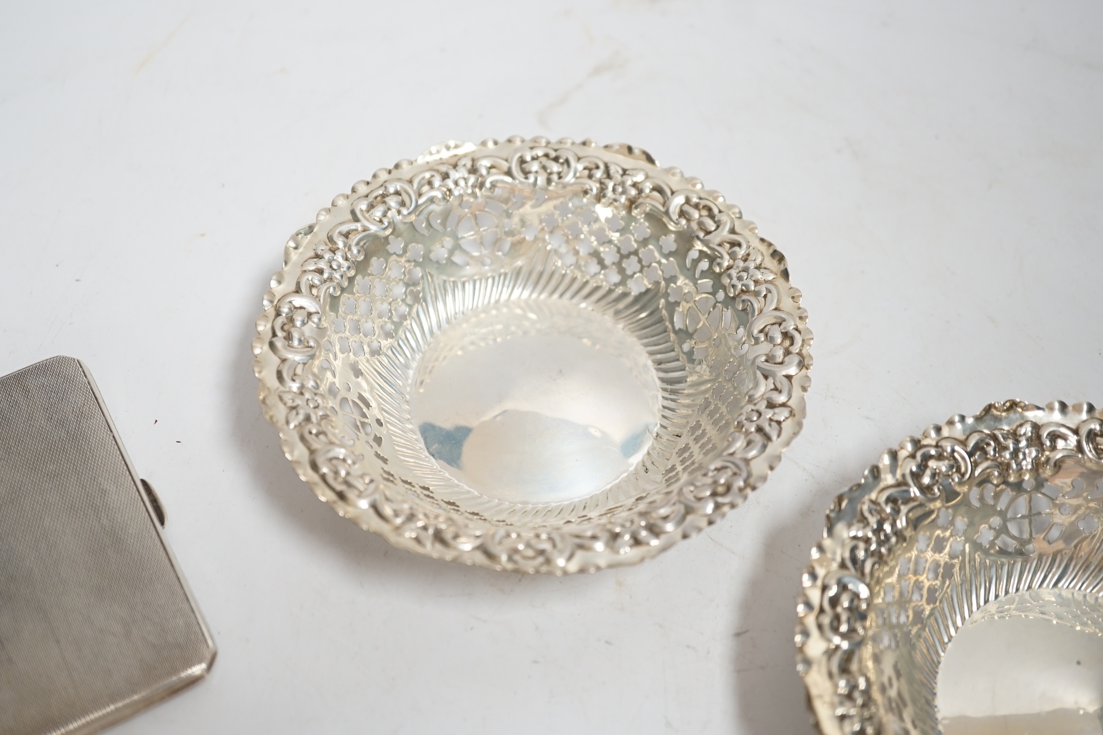 A pair of late Victorian pierced silver bonbon dishes, Birmingham, 1896, diameter 11.1cm, together with two silver cigarette cases.